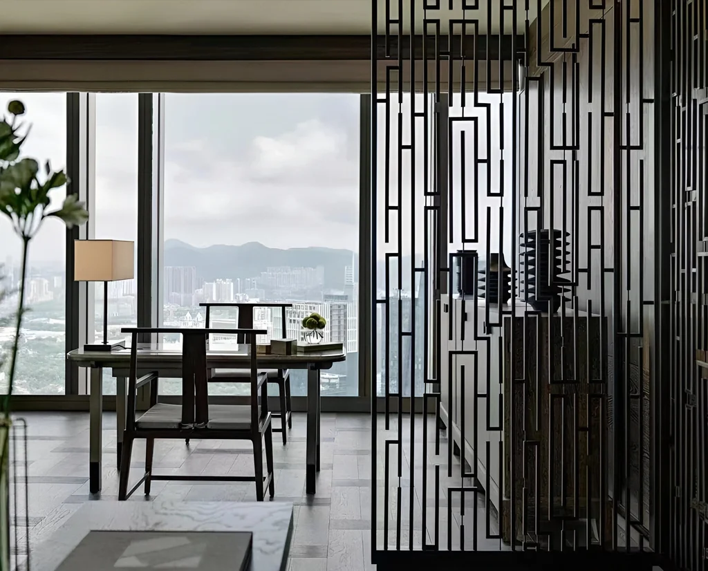 Blackened steel fret-pattern screen dividing an executive office lounge with a city skyline beyond