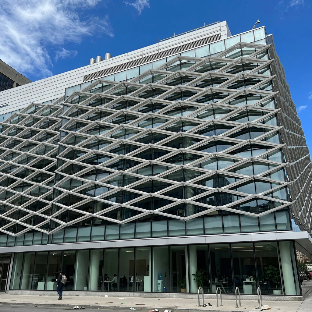 Diamond-lattice expanded metal solar shading screen across a glazed office facade — visualization