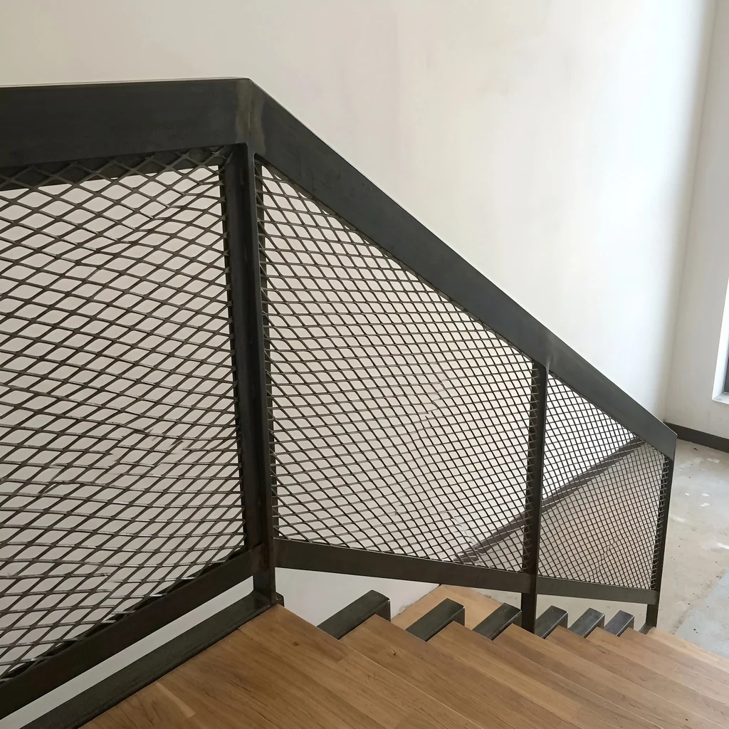 Expanded metal mesh infill in a blackened steel stair balustrade over timber treads — visualization